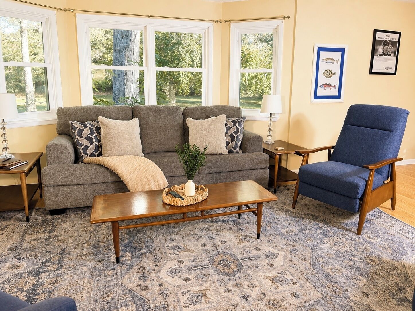 A living room with a grey sofa, a blue armchair, a wooden coffee table, and a patterned rug.