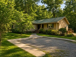 A single-story house with a front porch, a gravel driveway, and a well-maintained lawn.