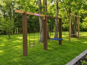 A wooden swing set in a park with a sign labeled 'FLAMINGO'.
