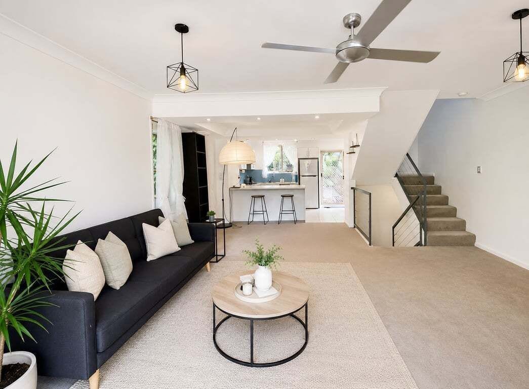 Un salon moderne avec un canapé, une table basse et un escalier menant à la cuisine.