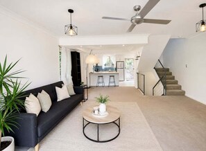 Un salon moderne avec un canapé, une table basse et un escalier menant à la cuisine.