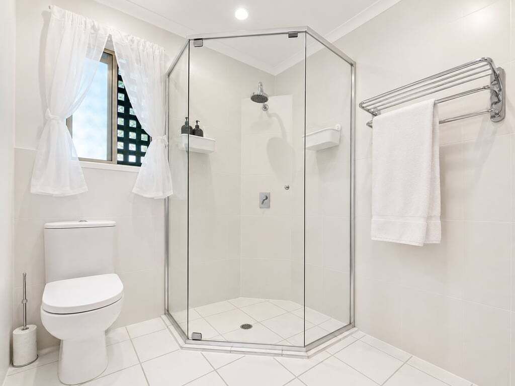 A modern bathroom with a glass-enclosed shower, a toilet, and a towel rack.