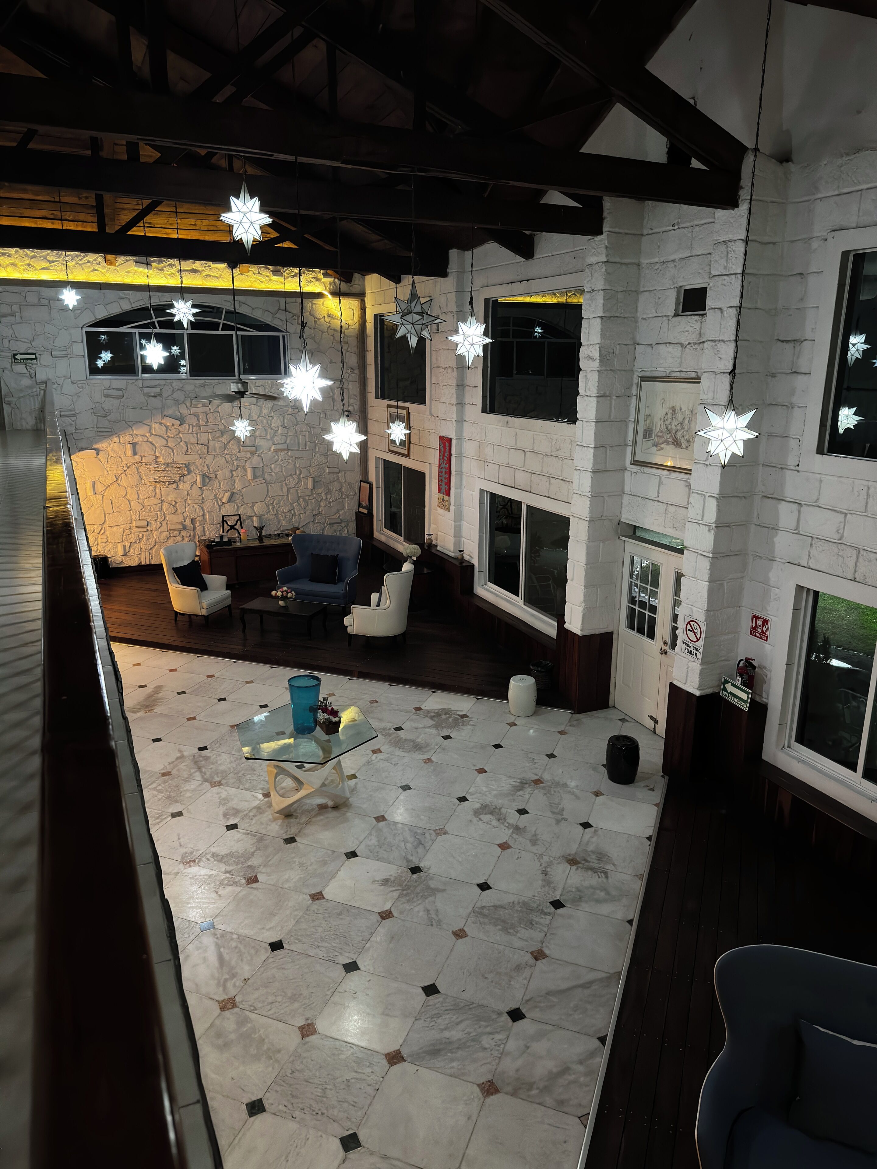 A spacious room with a stone wall, a fireplace, a dining area, and a balcony with a view.