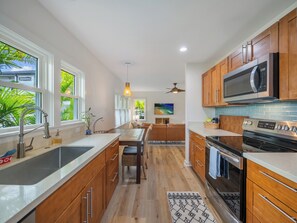 Une cuisine moderne avec des meubles en bois, un évier en acier inoxydable et un four à micro-ondes.
