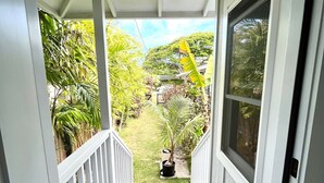 Eine Veranda mit Blick auf einen Garten, ein Paar Sandalen und ein Blumentopf.