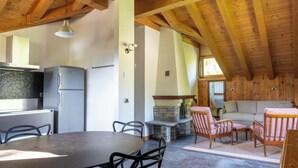 Una cocina con refrigerador, estufa y comedor con sillas y mesa.