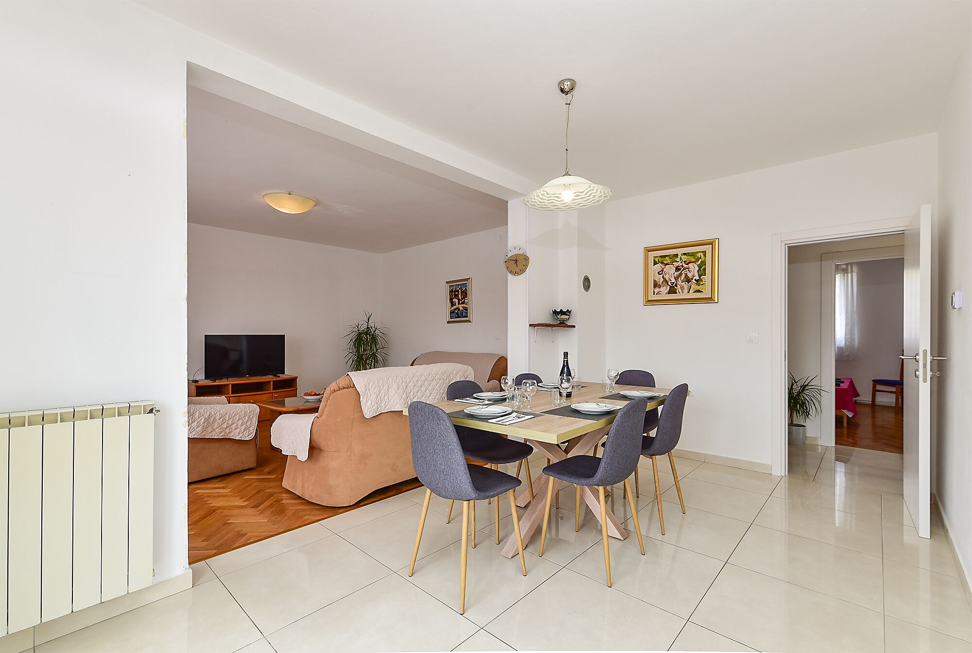 A modern living room with a dining area, a sofa, a TV, and a dining table with chairs.