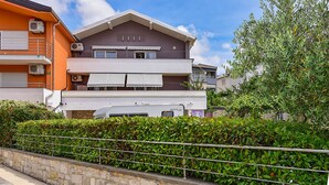 A multi-story residential building with balconies, air conditioning units, and a hedge in the foreground. - Apartment 2437/239180 (Istria - Pula), 1000m from the beach (Pula)