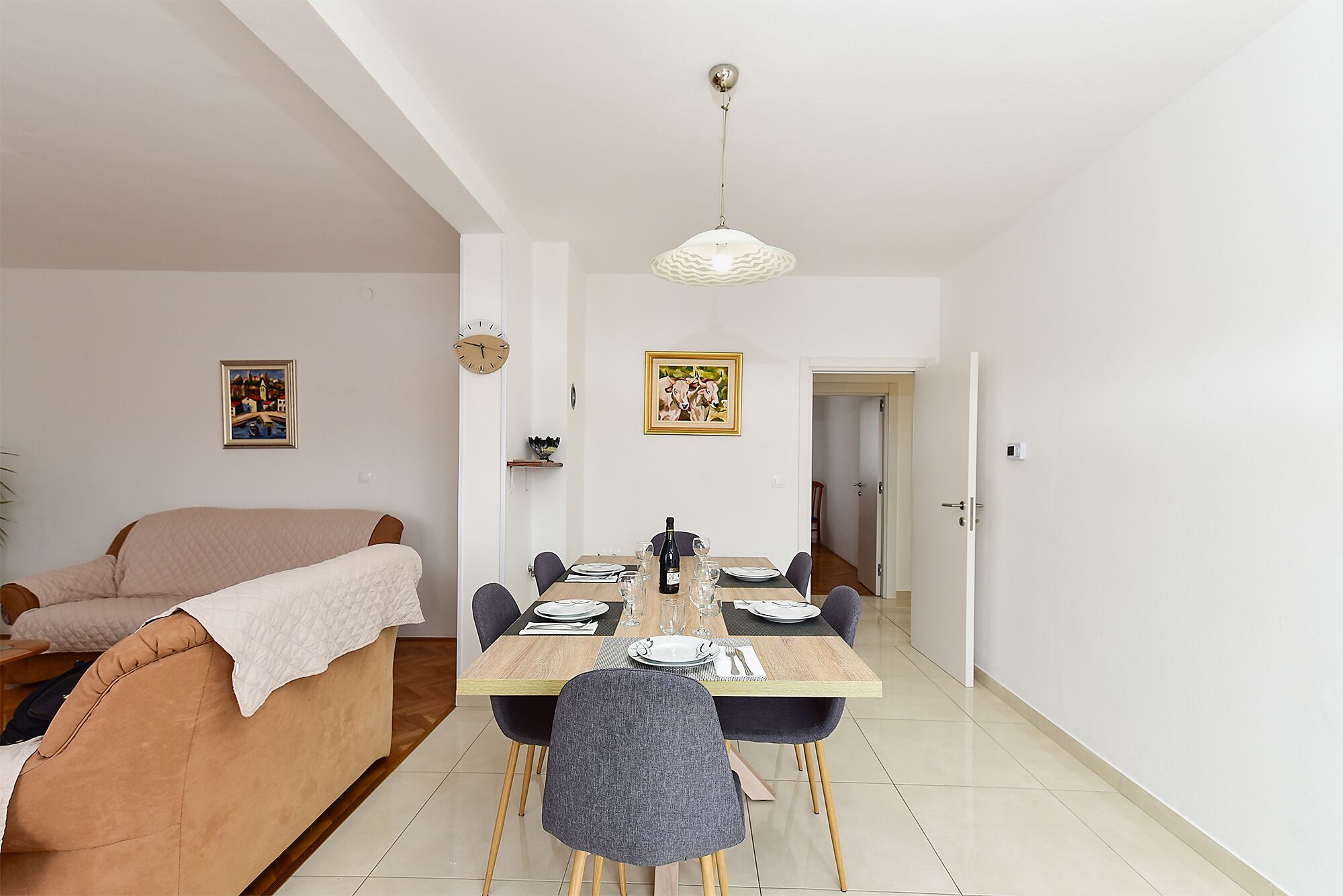 Un comedor con una mesa de madera, sillas y una lámpara colgante.