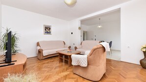 A living room with a sofa, armchair, and coffee table, a TV stand, and a potted plant. - Apartment 2437/239180 (Istria - Pula), 1000m from the beach (Pula)