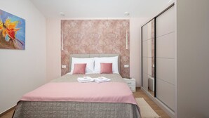 Un dormitorio con cama, mesitas de noche, un armario y un cuadro en la pared.