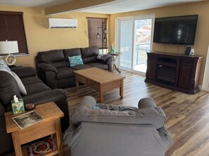 A living room with a sofa, a coffee table, a TV, and a sliding glass door. - 2-bedroom apartment in pleasant Fort Myers Beach with AC (Fort Myers Beach)
