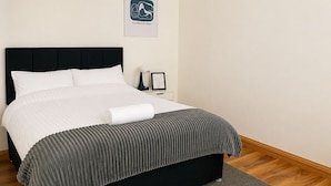 A neatly made bed with a black headboard, a grey striped blanket, and a white pillow. - Chic 5Bed City Centre Home-Sleeps9-Near QMC&Castle (Nottingham)