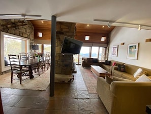 Amplia sala de estar con chimenea de piedra, televisor, sofá y mesa de comedor con sillas.