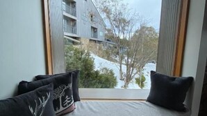 A window seat with cushions, a view of buildings, and a patterned floor. - Alpine Woodsmoke  (Falls Creek)