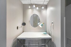 A small, modern room with a white desk, a round mirror, and a teal desk lamp. - Walk to Ocean | Luxury 2BR w/ King Master & Pool (Sunny Isles Beach)