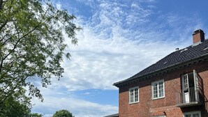 A large brick building with multiple windows and a door, surrounded by a well-maintained lawn. - Historic Copenhagen Villa with Garden (København)