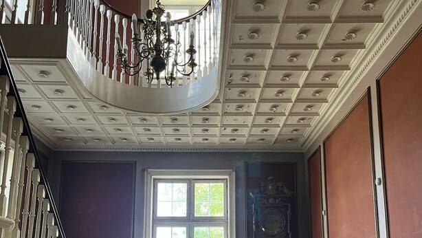 A room with a staircase, a large window with a plant, a radiator, a sofa, and a bookshelf. - Historic Copenhagen Villa with Garden (København)