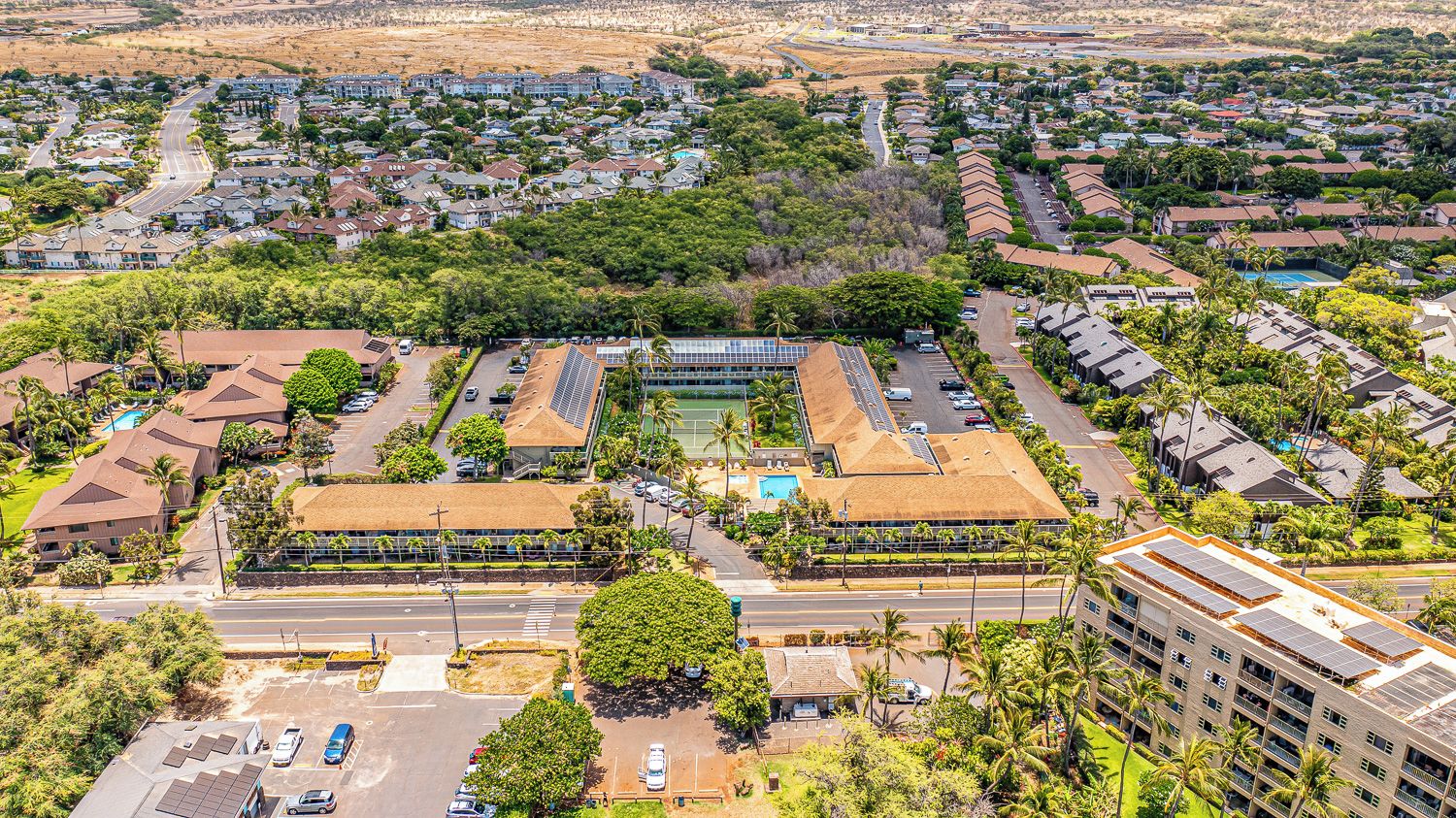 Vista aérea de una zona residencial con varios edificios, carreteras y zonas verdes.