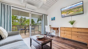 Ein modernes Wohnzimmer mit einer Couch, einem Couchtisch, einem Schreibtisch und einem an der Wand befestigten Fernseher.