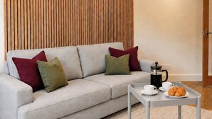 Una sala de estar moderna con un sofá, almohadas, una mesita de centro con una bandeja y una pared con listones de madera verticales.