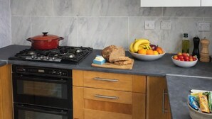 Eine moderne Küche mit Gasherd, Backofen, Holzschränken, Marmorfliesenspiegel und einem weißen Schrank.