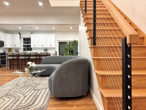 A modern interior with a staircase, grey sofas, a dining area, and a kitchen. - Luxury Retreat with Heated pool, sauna and jacuzzi (Covington township)