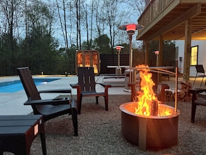 A poolside area with outdoor seating, a fire pit, and a covered deck. - Luxury Retreat with Heated pool, sauna and jacuzzi (Covington township)