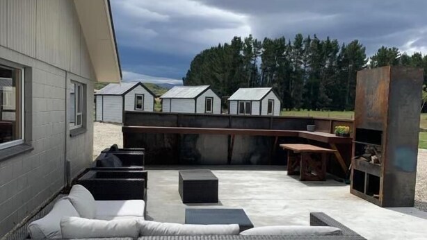 En takterrass med en stor soffa av rotting, ett litet bord och en bar.