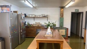 Une cuisine équipée d’appareils électroménagers en acier inoxydable, avec une table en bois et un meuble vert.
