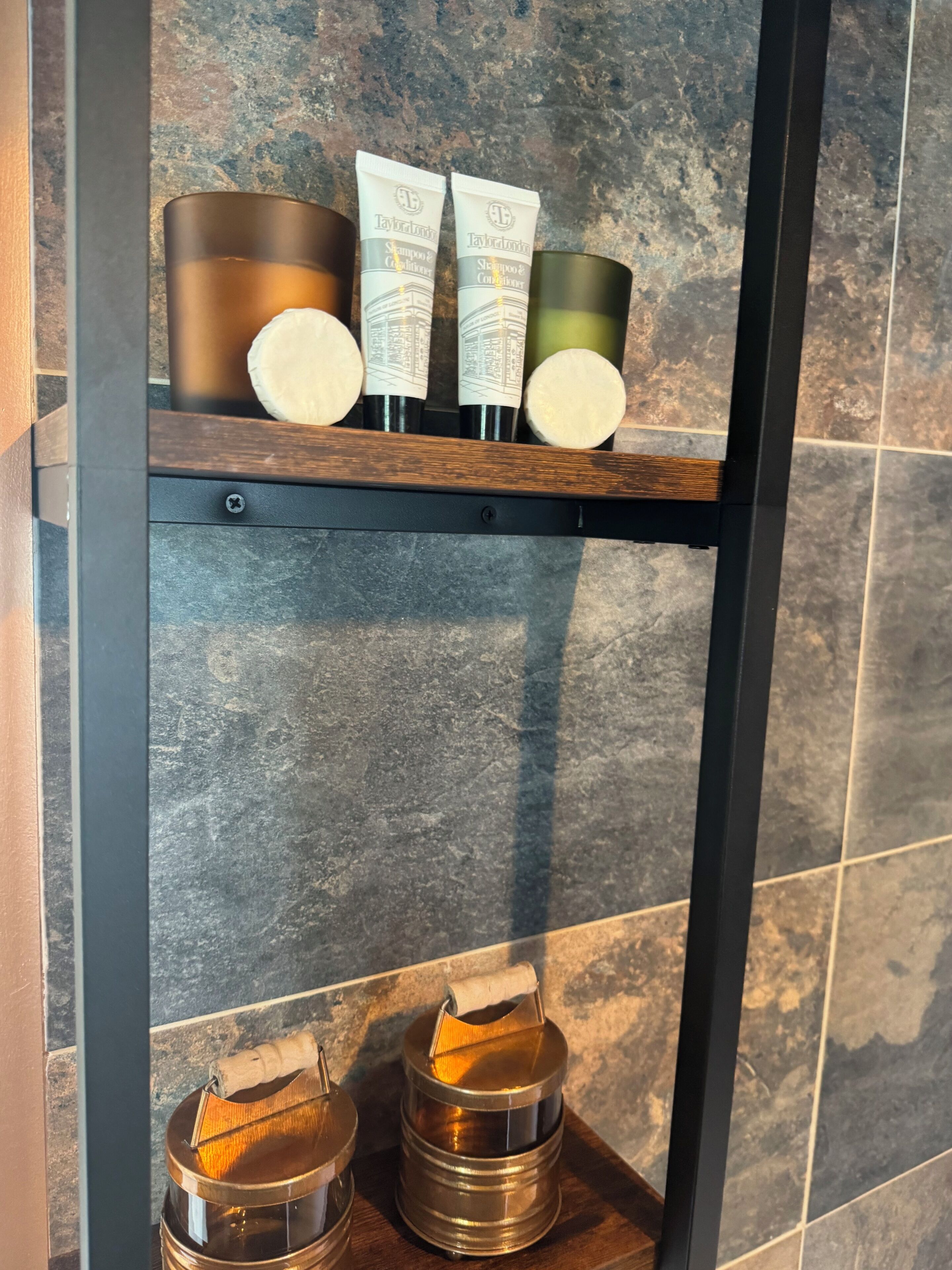 Une étagère avec trois produits de toilette et deux récipients en métal.