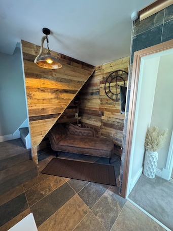 A staircase with a wooden wall design, a tufted sofa, and a decorative wall clock.. Superb 2-bedroom house
close to Leeds City Centre, stunning decor and Jacuzzi..