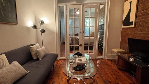 A living room with a glass-top coffee table, a sofa, a television, and a fireplace. - Stay with a local in Brownstone Brooklyn's Carroll Gardens (Brooklyn)