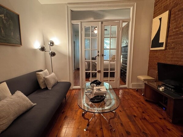 A living room with a glass-top coffee table, a sofa, a television, and a fireplace. - Stay with a local in Brownstone Brooklyn's Carroll Gardens (Brooklyn)