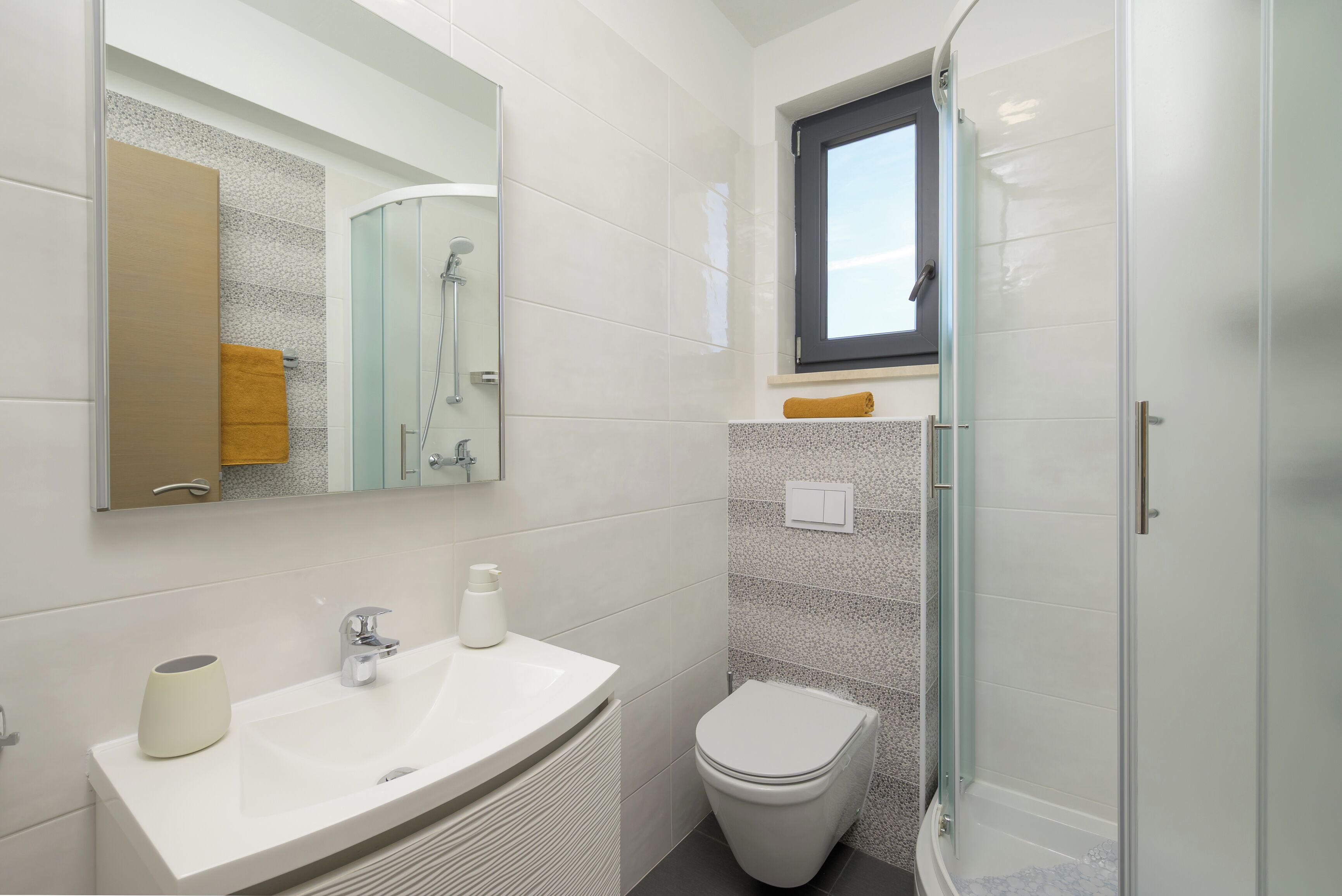 A modern bathroom with a glass shower enclosure, a white sink, and a toilet.