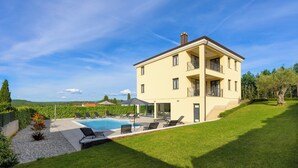 Ein zweistöckiges Haus mit Swimmingpool, Außenbereich und gepflegtem Rasen.