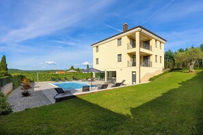 Ein zweistöckiges Haus mit Swimmingpool, Außenbereich und gepflegtem Rasen.