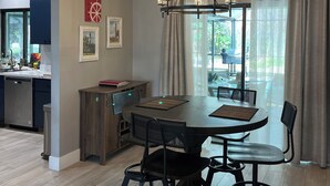 Een eetgedeelte met een ronde tafel, stoelen, een kroonluchter en uitzicht op de omgeving.
