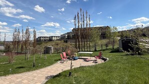 A paved pathway leading to a patio area with outdoor seating and a view of residential buildings in the background. - 2 Bed Room, 1 Bath, Living, Kitchen, Office, Bright, Walkout Basement Suite (Calgary)