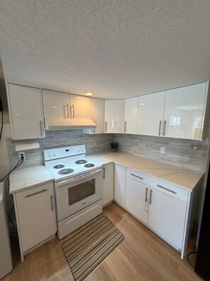 A modern kitchen with white cabinets, a white stove, and a tiled backsplash.