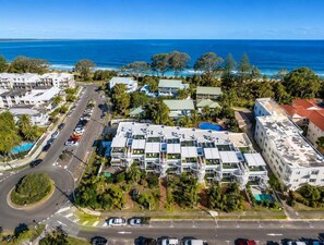 An aerial view of a coastal hotel with multiple buildings, a parking lot, and a road leading to the beach. - Relax & Unwind 2BR w/ Parking Maroochydore Beach (Sunshine Coast)