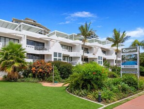 A modern hotel with multiple balconies, lush greenery, and a clear blue sky. - Relax & Unwind 2BR w/ Parking Maroochydore Beach (Sunshine Coast)