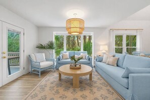 Ein Wohnzimmer mit einem blauen Sofa, einem blauen Sessel, einem runden Couchtisch und einer Pendelleuchte.