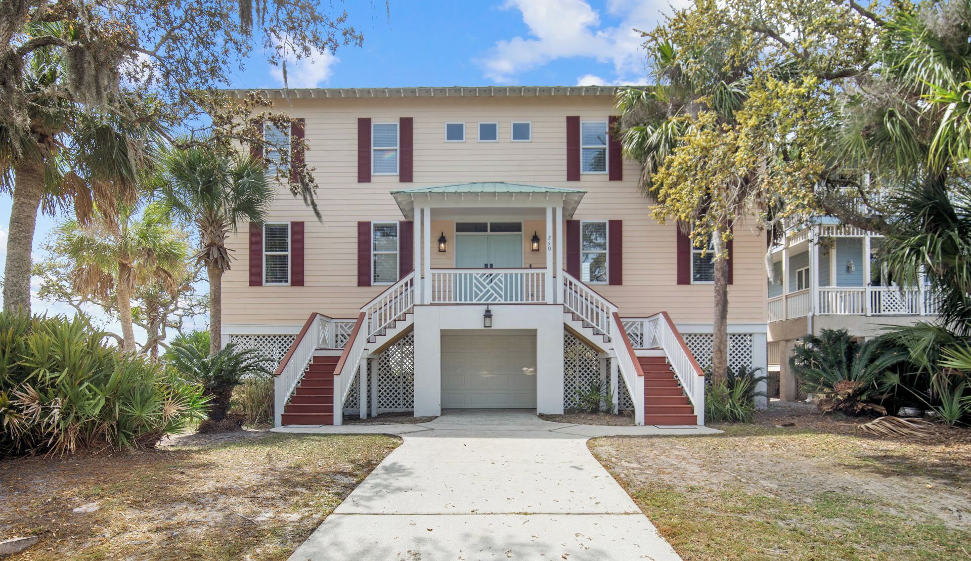 A two-story house with a front porch, a garage, and a pathway leading to the entrance.