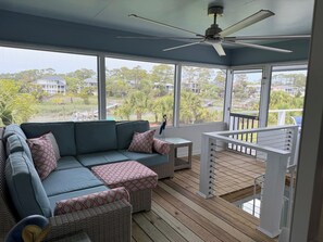 Eine überdachte Veranda mit einer Couch, Hocker und einem Deckenventilator.