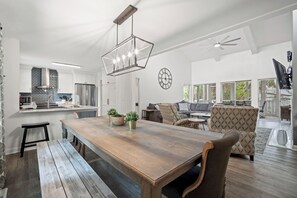 Una cocina moderna con electrodomésticos de acero inoxidable, una mesa de comedor de madera y un reloj grande en la pared.