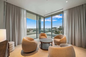 A modern hotel room with a panoramic city view, plush seating, and a large window. - RISE | Luxury Penthouse with Pool (Coolangatta)