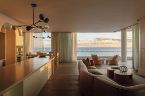 A modern kitchen with a view of the sea, a cozy seating area, and a large window with curtains. - RISE | Luxury Penthouse with Pool (Coolangatta)