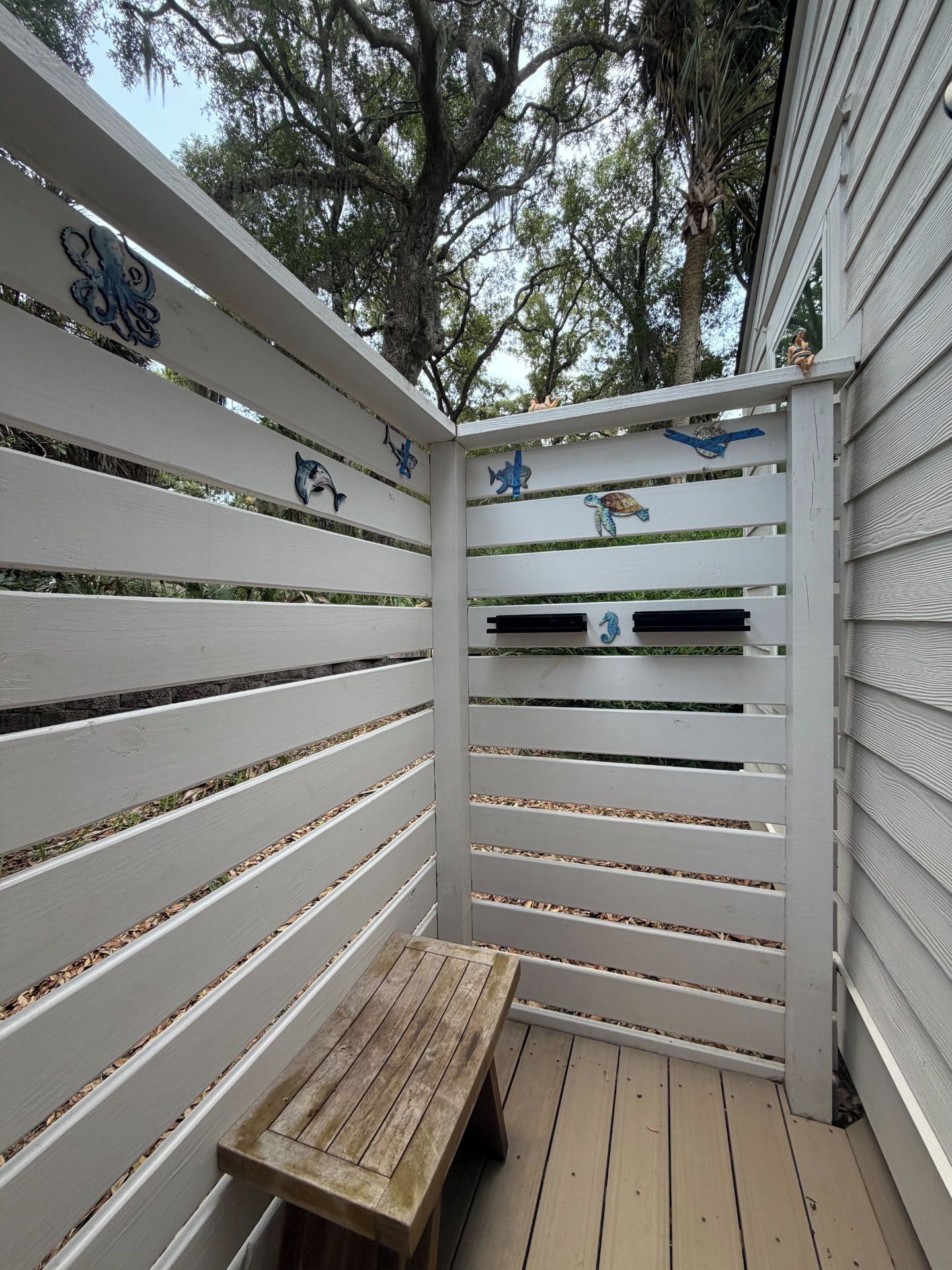 A wooden deck with a bench, white slatted fence, and decorative fish carvings.
