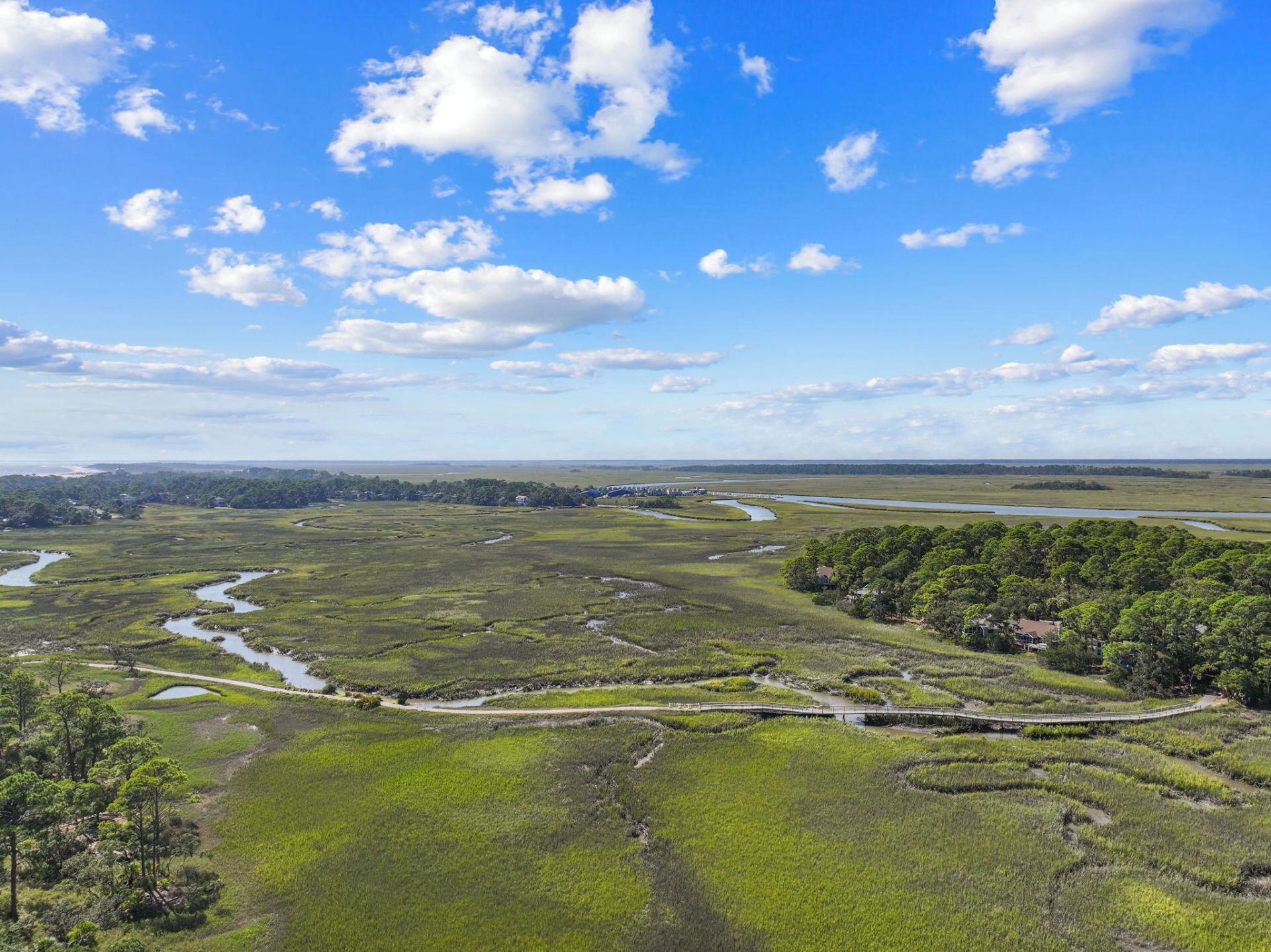 A coastal landscape with a bridge, marshy areas, and a distant shoreline.